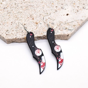 Detail of gothic acrylic earrings featuring a bloody cleaver knife with red splatter pattern