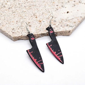 Detail of gothic acrylic bloodstained knife earrings on a natural stone background