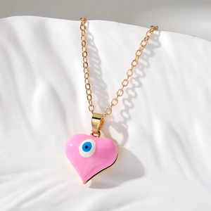 Dettaglio del ciondolo a cuore rosa con malocchio e catena dorata su sfondo a onde