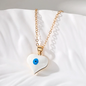 Dettaglio della collana dorata a cuore con malocchio su vassoio in ceramica