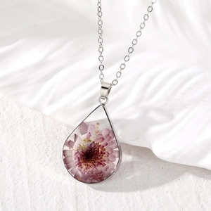 Macro view of teardrop resin pendant with dried flowers and silver O-chain