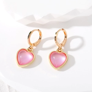 Détail des boucles d'oreilles cœur rose nacré avec fermoir en métal doré poli
