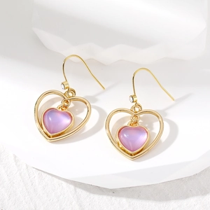 Détail de boucles d'oreilles dorées avec cœur violet et accent en zircon blanc