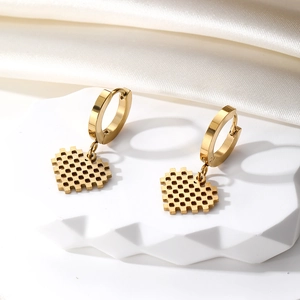 Golden pixel heart hoop earrings in stainless steel on a white geometric display stand