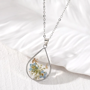 Close-up of teardrop resin pendant with real blue dried flowers and gold foil flakes