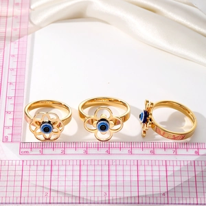 Trois bagues vintage dorées avec l'œil maléfique et motifs floraux sur soie blanche
