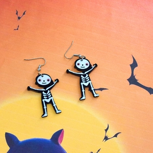 Detail shot of Halloween skeleton earrings made of acrylic on a festive orange backdrop