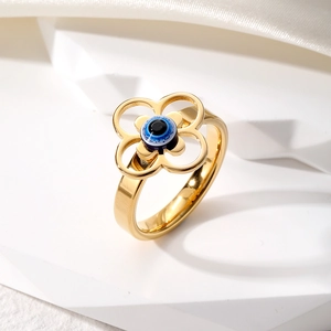 Détail d'une bague fleur évidée vintage avec un œil maléfique bleu sur anneau doré
