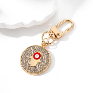 Golden Hamsa hand and evil eye keychain with sparkling rhinestones on white background