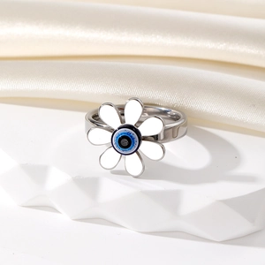 Détail d'une bague marguerite vintage argentée avec œil bleu sur tissu blanc