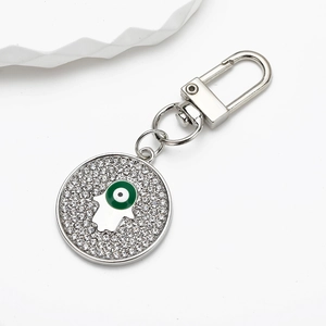 Macro detail of silver Hamsa Hand keychain with crystal pavé and blue evil eye charm