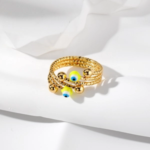 Dettaglio anello dorato a più strati con perline Evil Eye gialle e fasce testurizzate