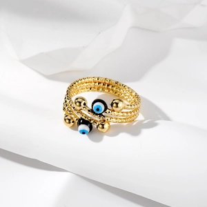 Dettaglio dell'anello Evil Eye dorato multistrato con ciondoli in smalto e fasce strutturate