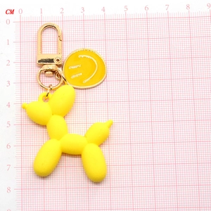 Portachiavi cane palloncino giallo con ciondolo sorridente su scala graduata rosa