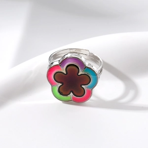 Bague fleur argentée ajustable avec pétales thermosensibles changeant de couleur sur tissu blanc