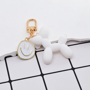 Dettaglio portachiavi cane palloncino bianco opaco con ciondolo smiley dorato e gancio
