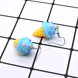 Detail shot of cute blue resin ice cream cone earrings with star sequins on grid background