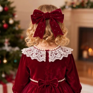 Mädchen im weinroten Samtkleid mit Spitzenkragen und Strass-Schleifen-Haarclip für Weihnachten