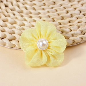 Close-up of handmade yellow chiffon flower with central pearl bead for DIY hair accessories