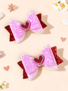 Dettaglio di fiocchi per capelli glitterati rosa con cuore di strass rosso su sfondo floreale