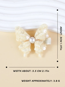 Macro d'une pince à cheveux papillon en dentelle crème avec perle et détails de taille
