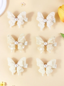 Détail de barrettes nœuds en dentelle crème avec perles et pinces crocodiles en métal