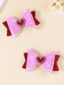 Dettaglio ravvicinato di fiocchi glitterati per capelli con cuore di strass rosso lucido