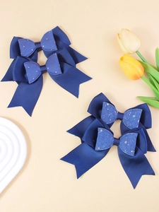 Detail of four dark blue glitter bow hair clips with ribbed texture and serrated edges