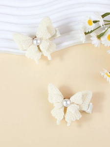 Gros plan détaillé de pinces à cheveux en dentelle crème avec perle sur plateau blanc