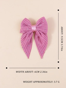 Macro shot of pink mesh bow hair clip with rhinestones and size labels in inches