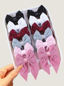 Detail shot of textured bow hair clips with sequins and satin ribbons in various colors
