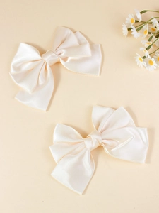 Detail of cream oversized silk satin bow hair clips with multi-layered folding texture