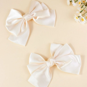 Pair of cream oversized satin bow hair clips for women with elegant silk texture