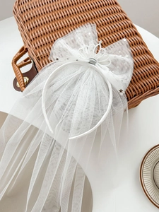 Detail of white girls' crown headband with mesh bow, silver stars and long trailing veil
