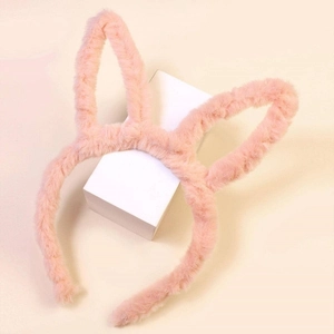 Détail d'un serre-tête oreilles de lapin en peluche rose sur support blanc épuré