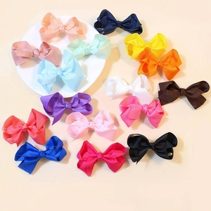 Mise à plat de 15 barrettes à nœuds en ruban gros-grain colorés sur fond beige clair