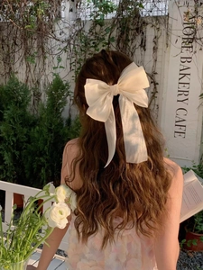 Détail d'un grand nœud en organza crème avec de longs rubans sur des cheveux bruns