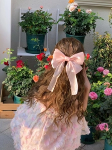 Pince à cheveux noeud rose en satin avec longs rubans sur cheveux longs ondulés
