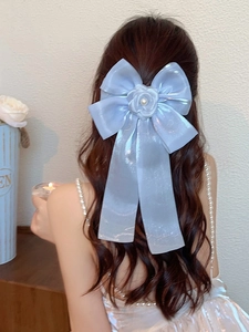 Detail of light blue bow hair clip with rose and pearl on long wavy brown hair