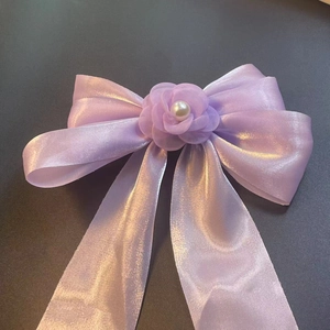 Detail of light purple satin bow hair clip with organza flower and pearl center