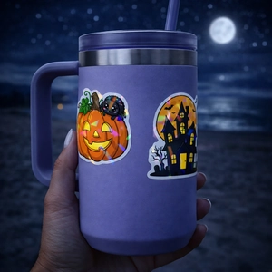 Purple Halloween stainless steel tumbler with spooky pumpkin decals and handle on beach background