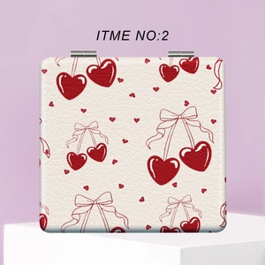 Close-up of portable makeup mirror with white faux leather and red heart print