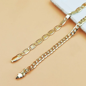 Detail of gold Figaro chain with heart engraving and classic Cuban link anklet