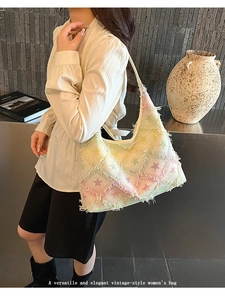 Detail of white denim tote bag featuring colorful gradient stars and tassel fringe finish