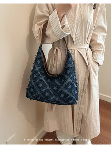 Detail of vintage denim tote bag with star patterns and frayed fringe edges worn by a model