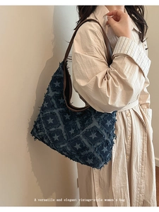 Detail of vintage denim tote bag showing frayed star patterns and brown leather strap