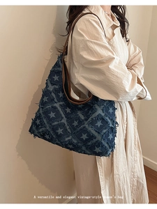 Detail of blue denim tote bag with star print patterns and brown leather straps