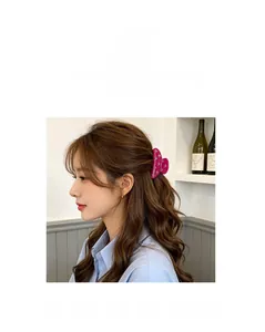 Détail d'une pince à cheveux rose avec strass portée sur les cheveux ondulés du modèle