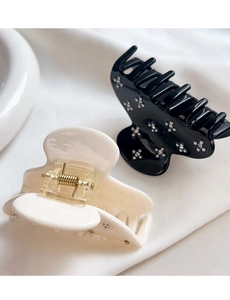 Detailed close-up of elegant acetate hair claw clips featuring rhinestone flower patterns