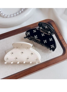 Close-up of acetate hair claw clips with rhinestone flower patterns on a wooden tray